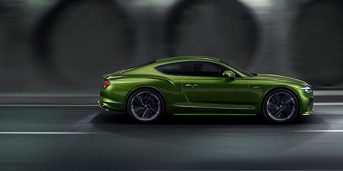  Bentley Hampshire Bentley Continental GT coupe in Tourmaline Green paint driving in profile on a dark road