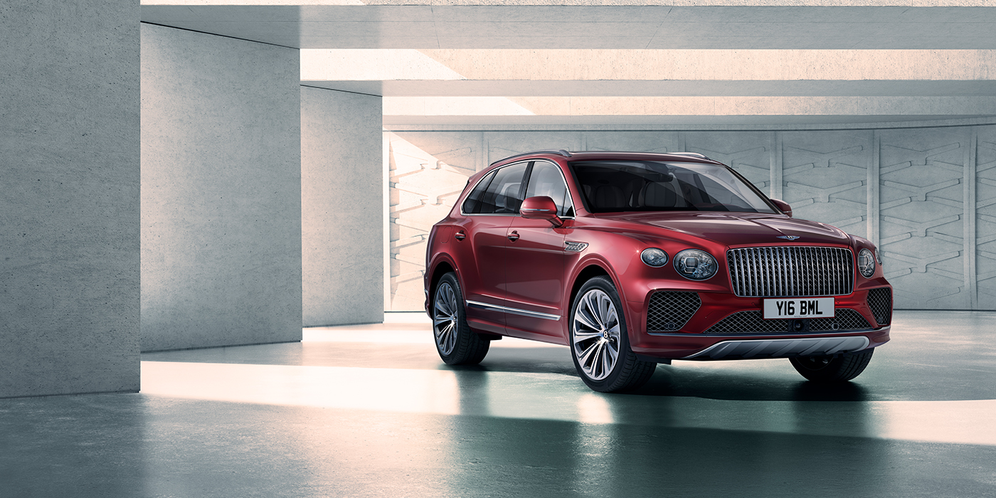 Bentley Hampshire Bentley Bentayga Atelier Edition SUV in Rubino Red paint front three quarter against textured concrete wall