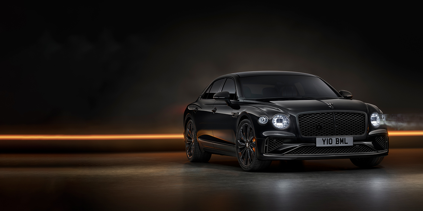 Bentley Hampshire Bentley Flying Spur Black Edition sedan in Black Crystal paint against a dark grey and copper coloured background