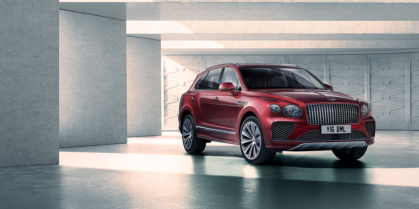 Bentley Hampshire Bentley Bentayga Atelier Edition SUV in Rubino Red paint front three quarter against textured concrete wall