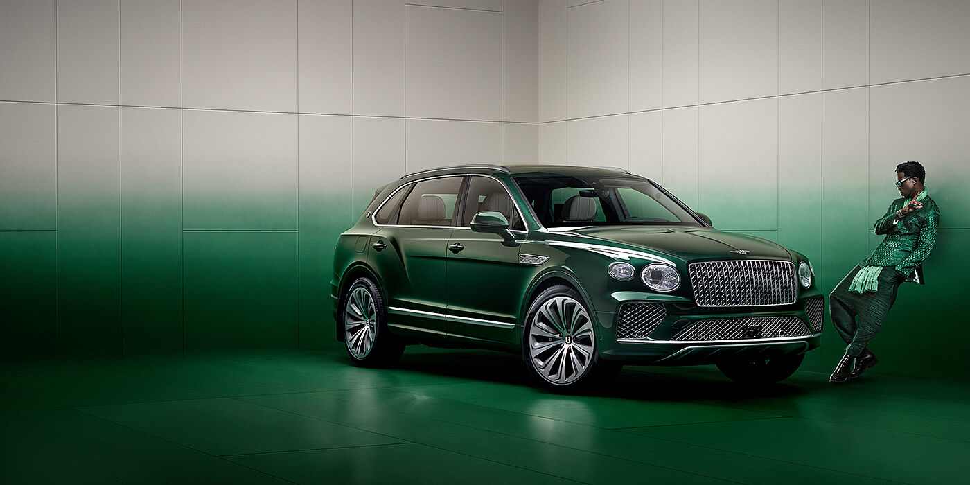 Bentley Hampshire Wisdom K leans against wall next to Bentley Bentayga Extended Wheelbase Atelier Edition SUV in Light Emerald green paint