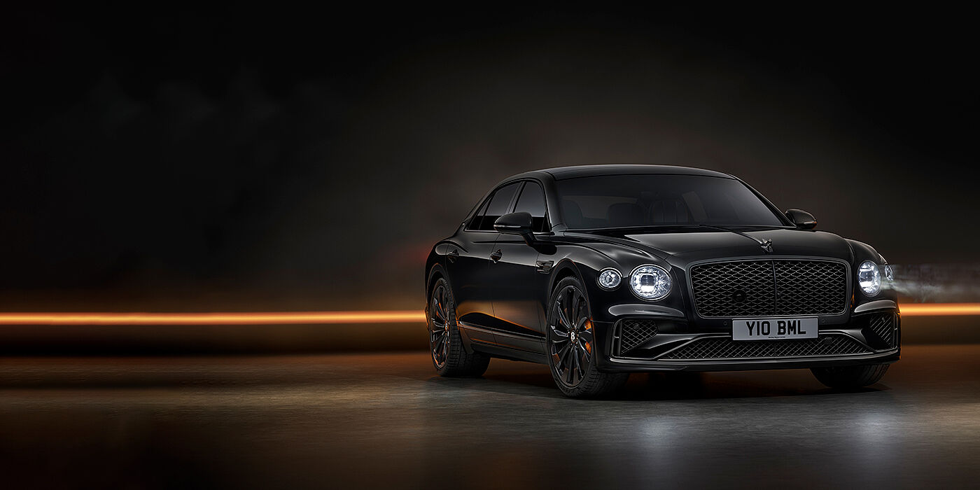 Bentley Hampshire Bentley Flying Spur Black Edition sedan in Black Crystal paint against a dark grey and copper coloured background