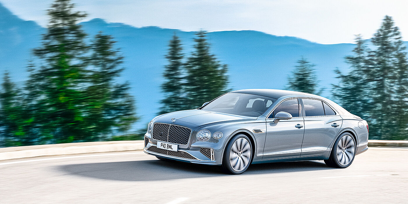 Bentley Hampshire New Bentley Flying Spur sedan side view in Silverlake paint with ten spoke wheels and chrome matrix grille driving dynamically on a mountain road