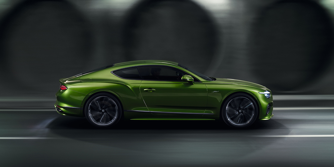 Bentley Hampshire Bentley Continental GT coupe in Tourmaline Green paint driving in profile on a dark road